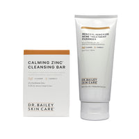 Dr. Bailey Skin Care Calming Zinc Cleansing Bar shown with its white and orange packaging box and the white squeeze tube of benzoyl peroxide acne treatment cleanser on a white background.